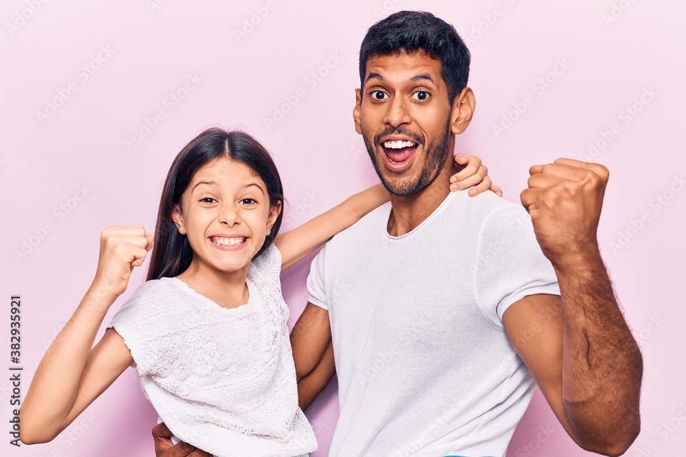 Young father and daughter wearing casual clothes celebrating surprised and amazed for success with arms raised and open eyes. winner concept. Young father and daughter wearing casual clothes celebrating surprised and amazed for success with arms raised and open eyes. winner concept.