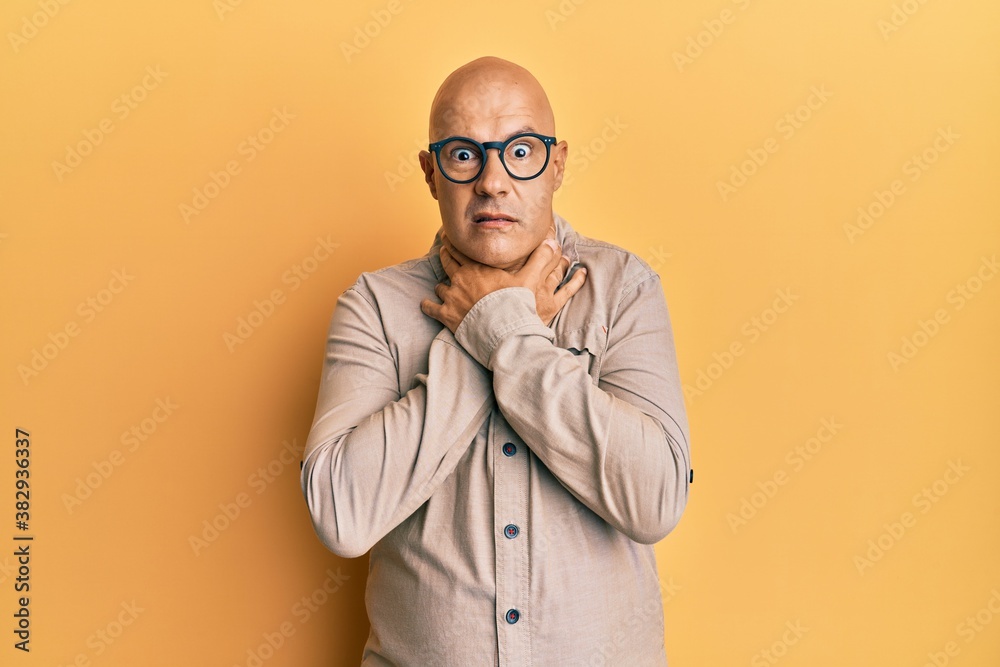 Middle age bald man wearing casual clothes and glasses shouting and suffocate because painful strangle. health problem. asphyxiate and suicide concept.