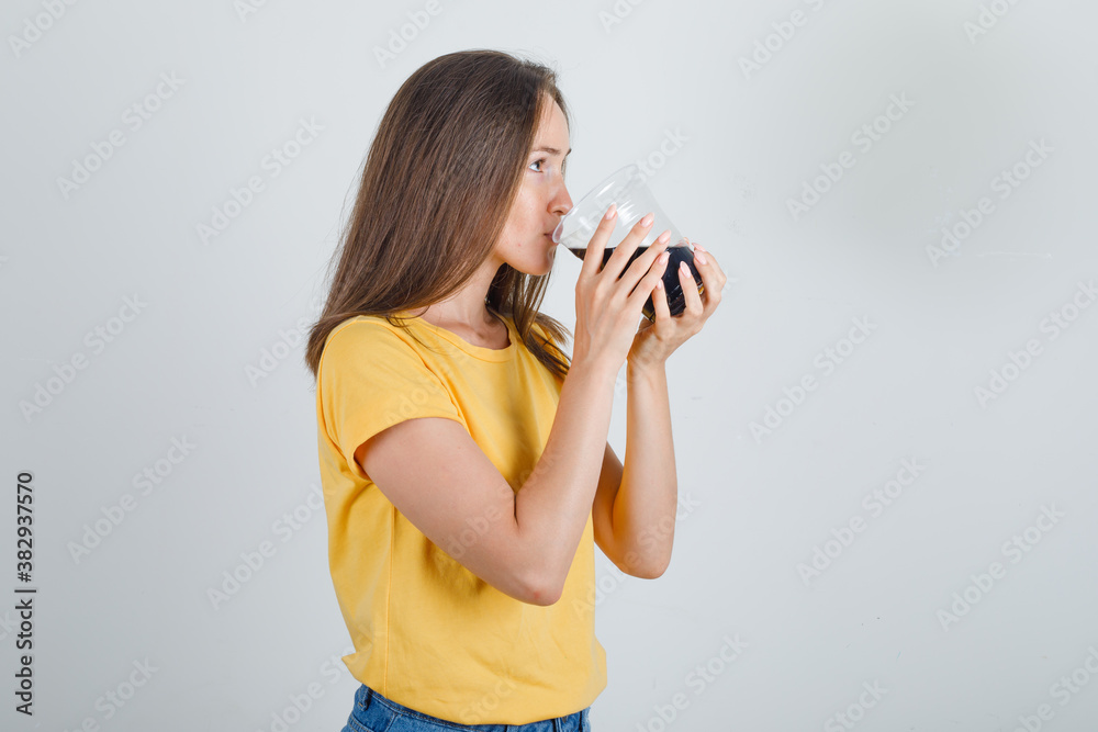 Young woman in t-shirt, shorts drinking cold cola and looking thirsty . Young woman in t-shirt, shorts drinking cold cola and looking thirsty .
