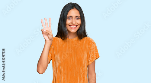 Young brunette arab woman wearing casual clothes showing and pointing up with fingers number three while smiling confident and happy.