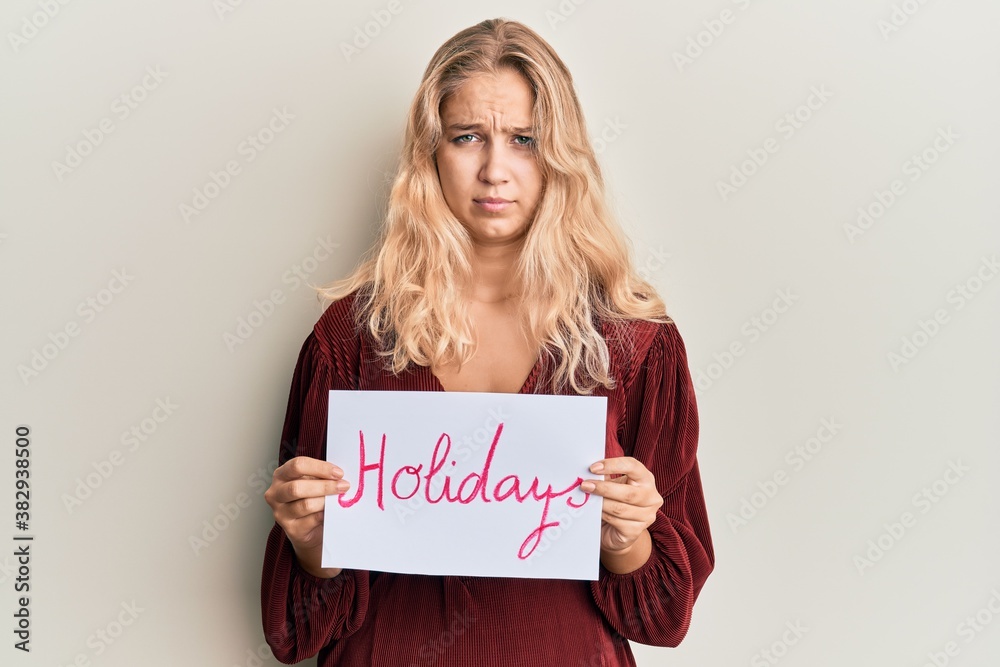 Young blonde girl holding holidays banner message skeptic and nervous, frowning upset because of problem. negative person. Young blonde girl holding holidays banner message skeptic and nervous, frowning upset because of problem. negative person.