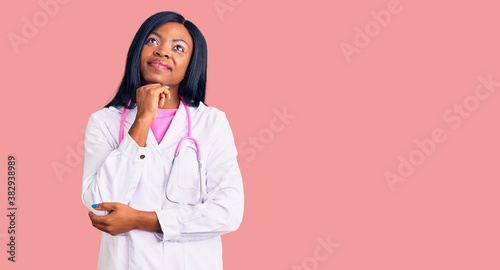 Young african american woman wearing doctor stethoscope with hand on chin thinking about question, pensive expression. smiling and thoughtful face. doubt concept.