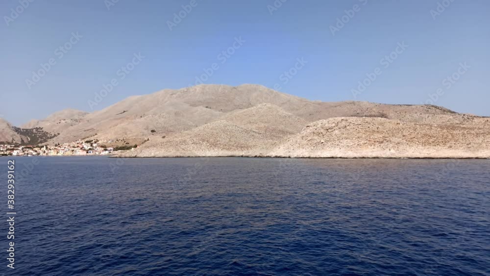 A ship slowly approaching Emporio port with houses barely visible on halki / chalki island on a hilly island of Greece in the Dodecanese archipelago in the Aegean Sea, some 6 km (4 mi) west of Rhodes A ship slowly approaching Emporio port with houses barely visible on halki / chalki island on a hilly island of Greece in the Dodecanese archipelago in the Aegean Sea, some 6 km (4 mi) west of Rhodes