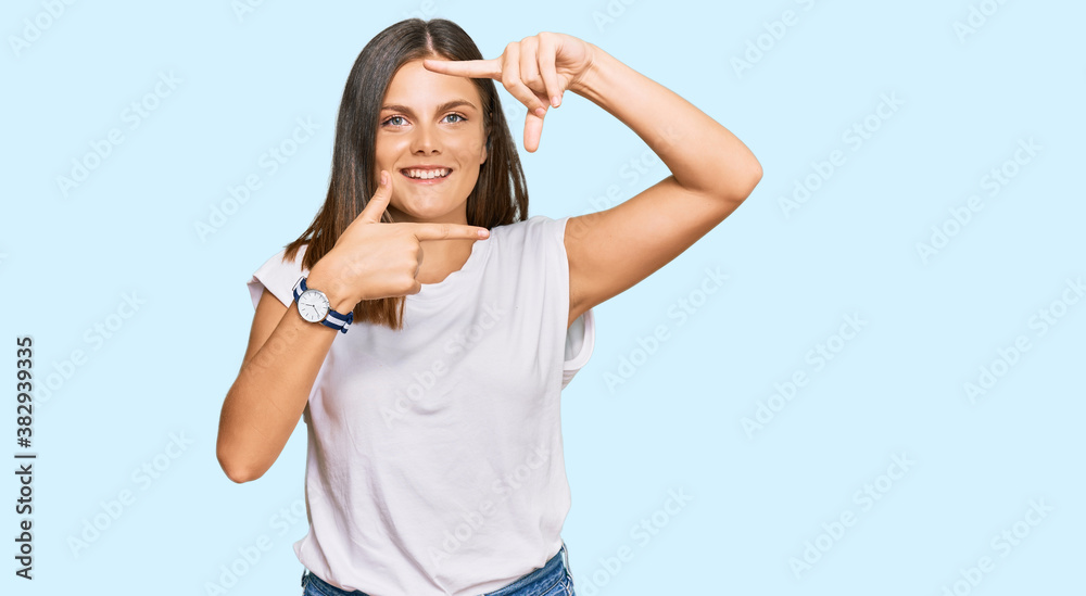 Young caucasian woman wearing casual white tshirt smiling making frame with hands and fingers with happy face. creativity and photography concept. Young caucasian woman wearing casual white tshirt smiling making frame with hands and fingers with happy face. creativity and photography concept.