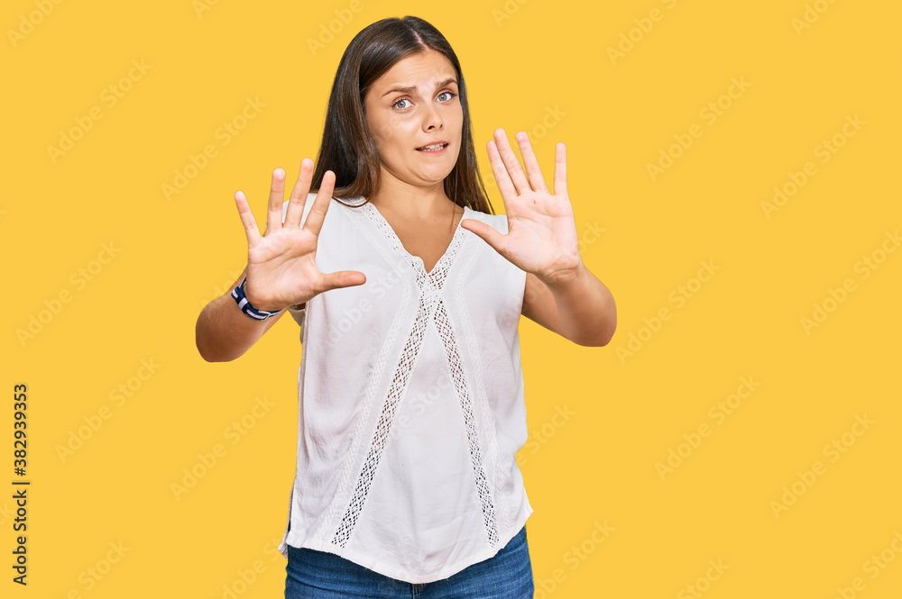 Young caucasian woman wearing casual clothes afraid and terrified with fear expression stop gesture with hands, shouting in shock. panic concept. Young caucasian woman wearing casual clothes afraid and terrified with fear expression stop gesture with hands, shouting in shock. panic concept.