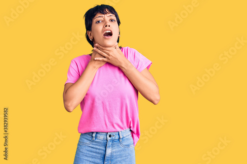 Young brunette woman with short hair wearing casual clothes shouting and suffocate because painful strangle. health problem. asphyxiate and suicide concept. © Krakenimages.com