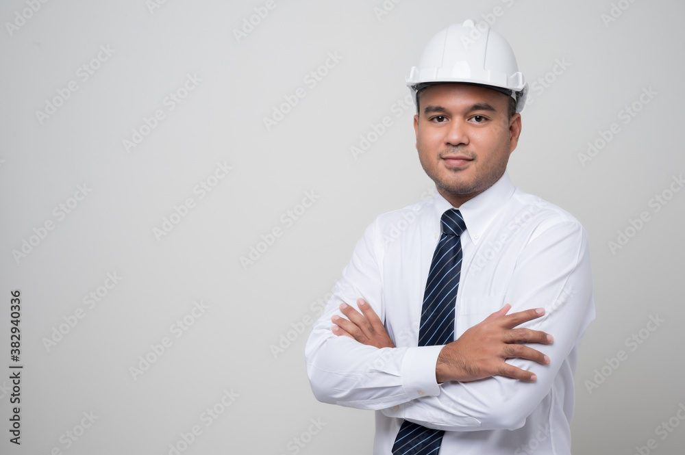 Smiling young asian civil engineer wearing safety helmet hard hat standing with arm crossed in studio. Mechanic service on isolated white background.. Smiling young asian civil engineer wearing safety helmet hard hat standing with arm crossed in studio. Mechanic service on isolated white background..