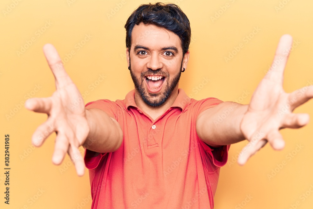 Young hispanic man wearing casual clothes looking at the camera smiling with open arms for hug. cheerful expression embracing happiness. Young hispanic man wearing casual clothes looking at the camera smiling with open arms for hug. cheerful expression embracing happiness.