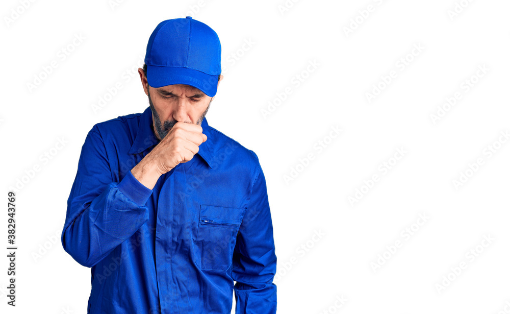 Middle age handsome man wearing mechanic uniform feeling unwell and coughing as symptom for cold or bronchitis. health care concept.