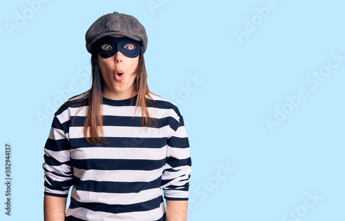 Young beautiful brunette woman wearing burglar mask afraid and shocked with surprise expression, fear and excited face. © Krakenimages.com