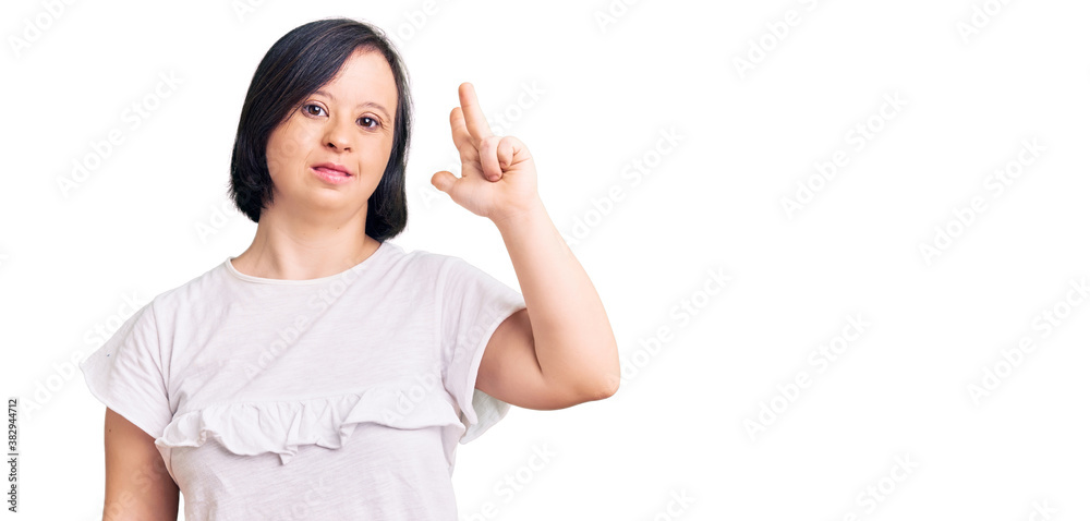 Brunette woman with down syndrome wearing casual white tshirt showing and pointing up with fingers number three while smiling confident and happy.