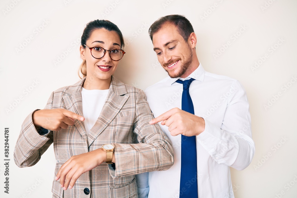 Beautiful couple wearing business clothes in hurry pointing to watch time, impatience, upset and angry for deadline delay Beautiful couple wearing business clothes in hurry pointing to watch time, impatience, upset and angry for deadline delay