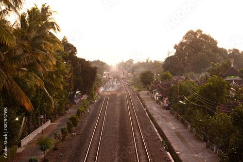 Fotografie train road in the afternoon with silhouettes of trees and orange sky