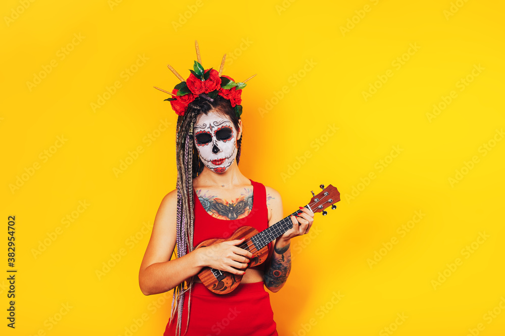A woman with make-up for the holiday of the day of the dead, a skull is painted on her head with a wreath and a guitar in her hands