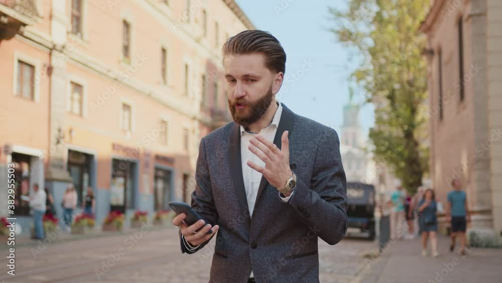 Shot of happy bearded man use phone read good new smiling on city street look around. Successful elegant confident portrait man. Entrepreneur leader. Slow motion