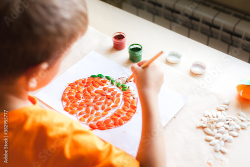 Making pumpkin from seeds on white paper, Halloween DIY concept. Step by step instruction Step 4 Paint the seeds with green color photo