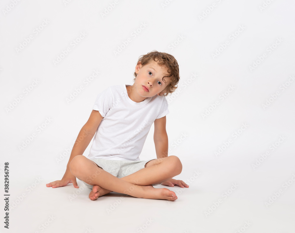 Serious young boy sitting cross legged with serious expression face isolated on white
