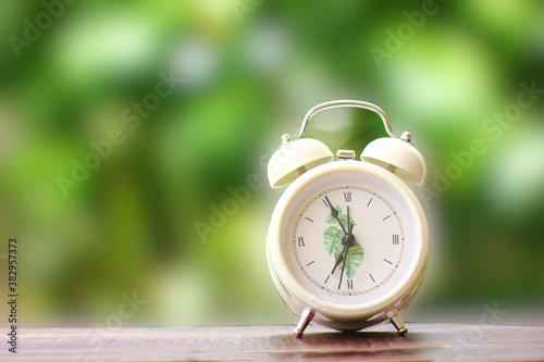 alarrm clock on wood floor with blur green background