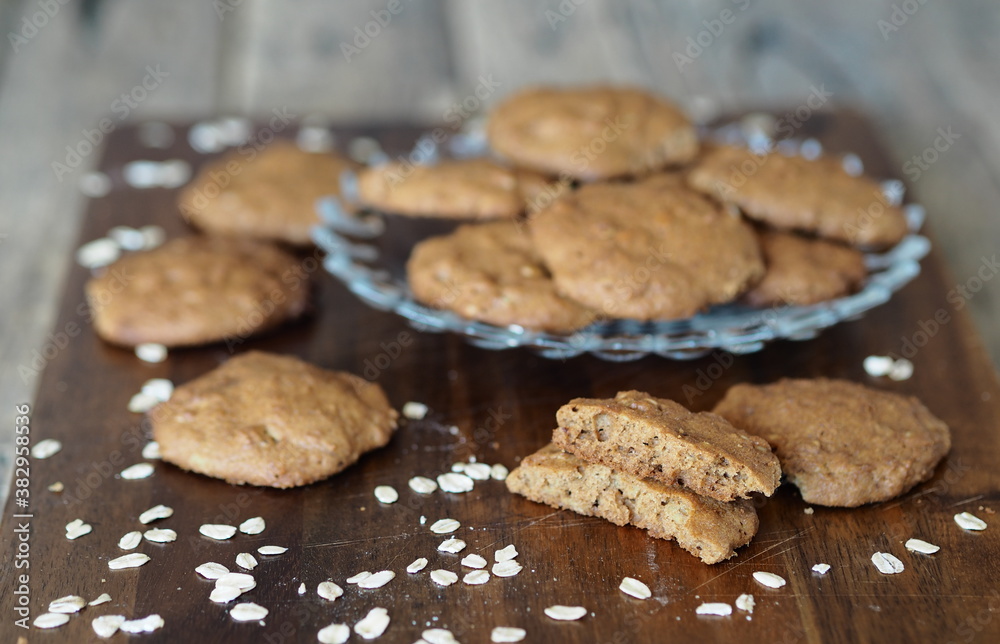 Homemade oatmeal cookies with whole grain rye flour in a glass plate on a wooden background. Diet healthy food.