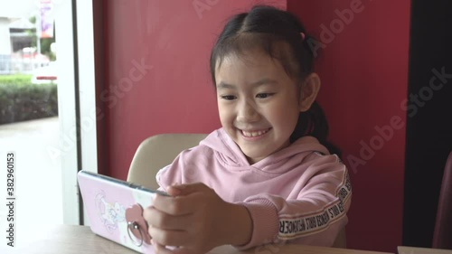 little kid using a smart phone and having a video call chatting or taking a selfie sitting  fun and enjoying online communication