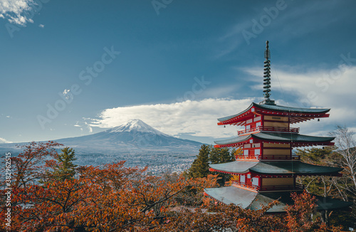 View from Chureito Pagoda in autumn, Fujiyoshida, Japan. There are many trees with red and orange color leaves. Fuji volcano in the back with snow on the peak on the clear sky. Copy space on top.