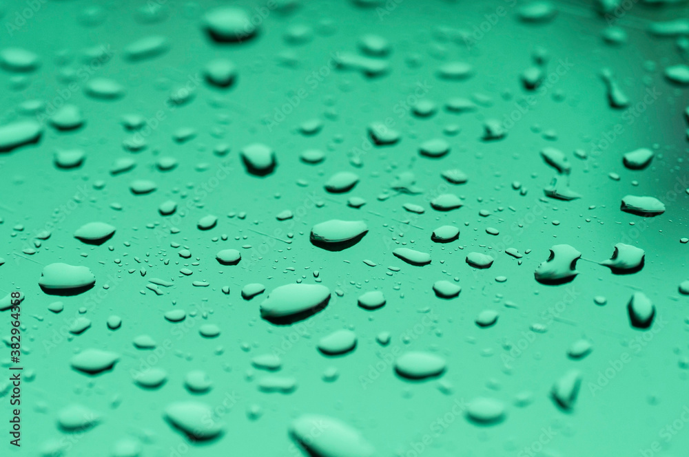 Water drop on mirror reflection with light made mor color blue green violet.