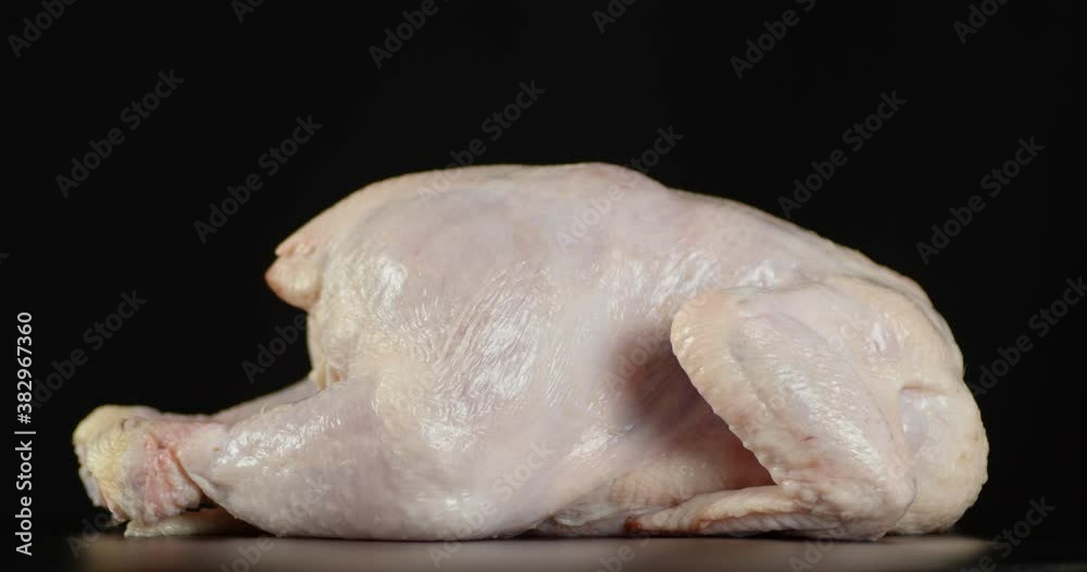 On the table slowly rotates raw whole chicken. On the table slowly rotates raw whole chicken.