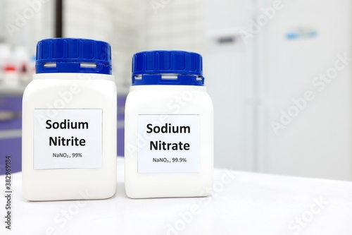 Selective focus of bottles of pure sodium nitrite and nitrate chemical compound preservative. White laboratory background with copy space.