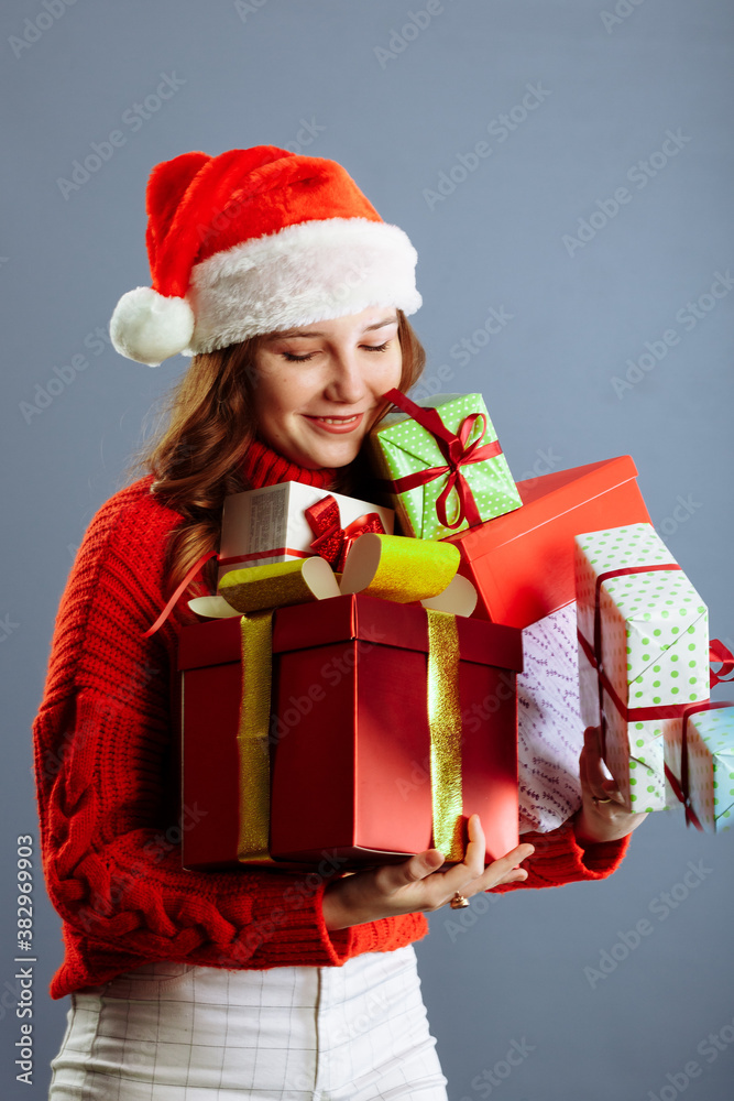 Joyful woman woman holding a lot of boxes with gifts on a gray background. Joyful woman woman holding a lot of boxes with gifts on a gray background.