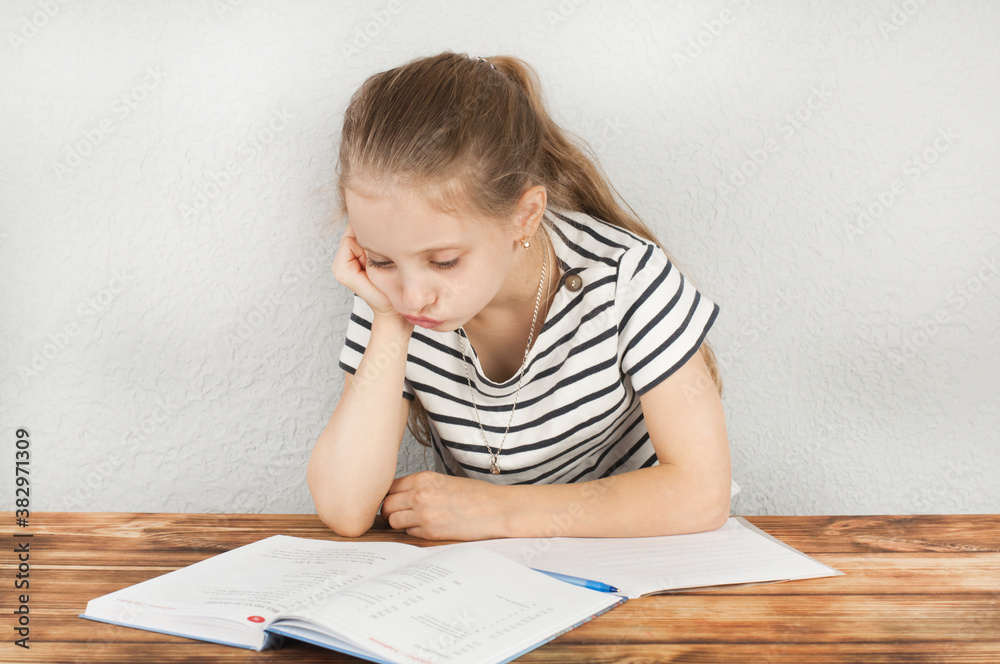 Girl 8 - 10 years old doing homework sitting at a wooden table. Homeschooling Girl 8 - 10 years old doing homework sitting at a wooden table. Homeschooling