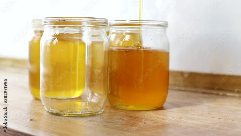 bee honey is poured into jars on a sunny day, background. Healing and sweet product, organic bee honey is poured into jars on a sunny day, background. Healing and sweet product, organic