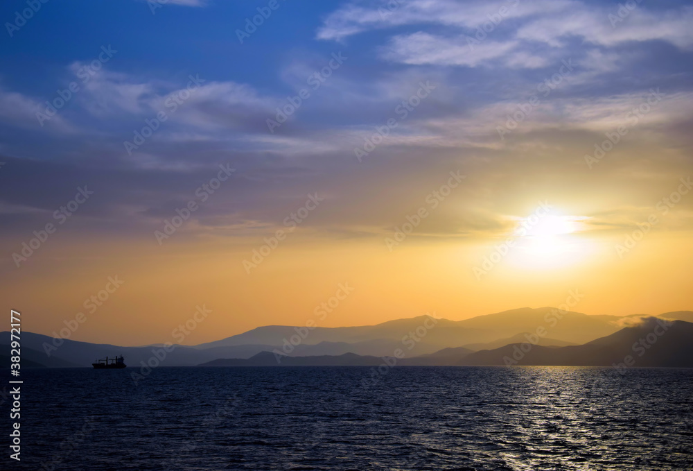 cargo ship travels at sunset