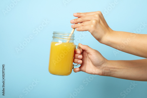 Female hands hold banana juice on blue background