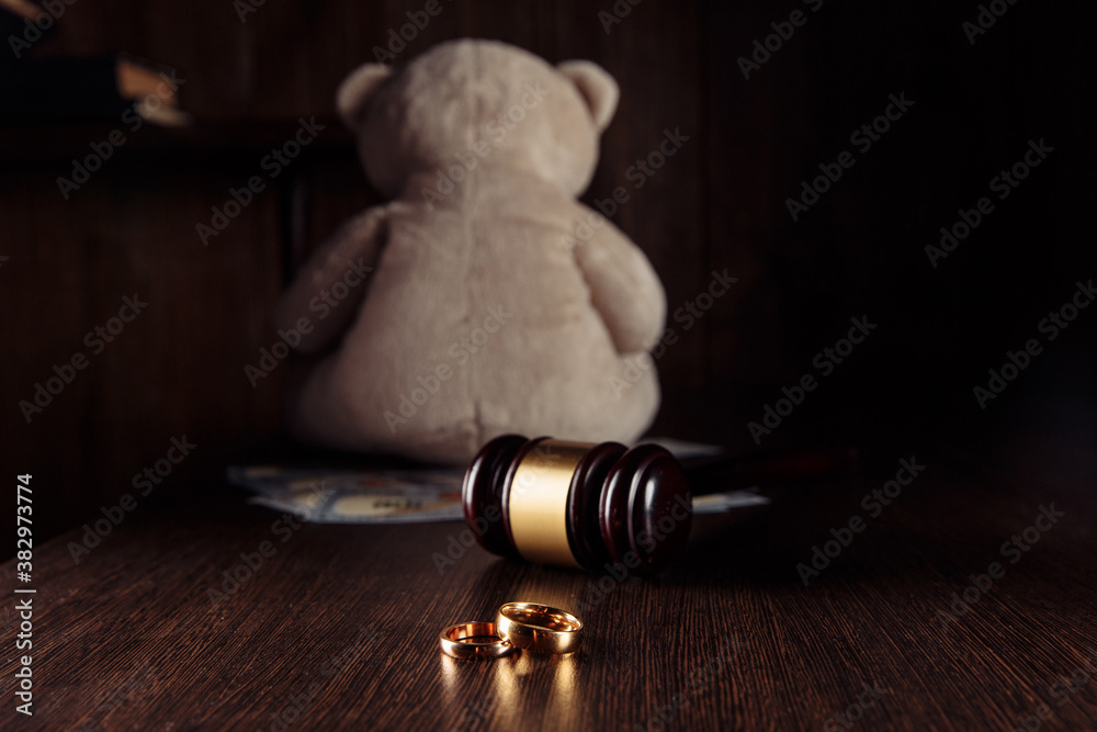 Wooden judge gavel with rings and teddy bear dollar banknotes. Divorce and alimony concept. Wooden judge gavel with rings and teddy bear dollar banknotes. Divorce and alimony concept.