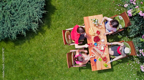 Family and friends eating together outdoors on summer garden party. Aerial view of table with food and drinks from above. Leisure, holidays and picnic concept
