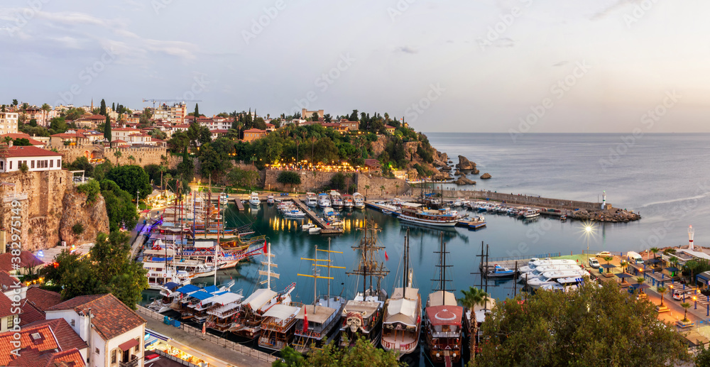 Fototapeta premium Panorama of the old city in Antalya, the old port in the harbor are yachts and ships, evening illumination of the city