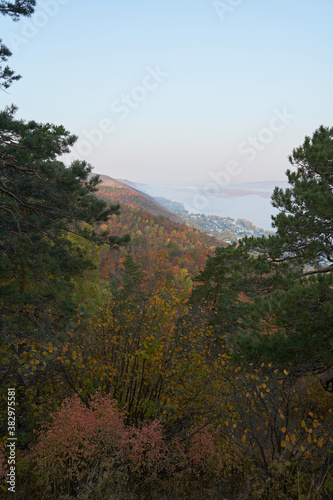 Autumn view from the mountain to the big river, in the forest with Golden leaves and green fir trees. Autumn time in the forest. © nikolay_alekhin