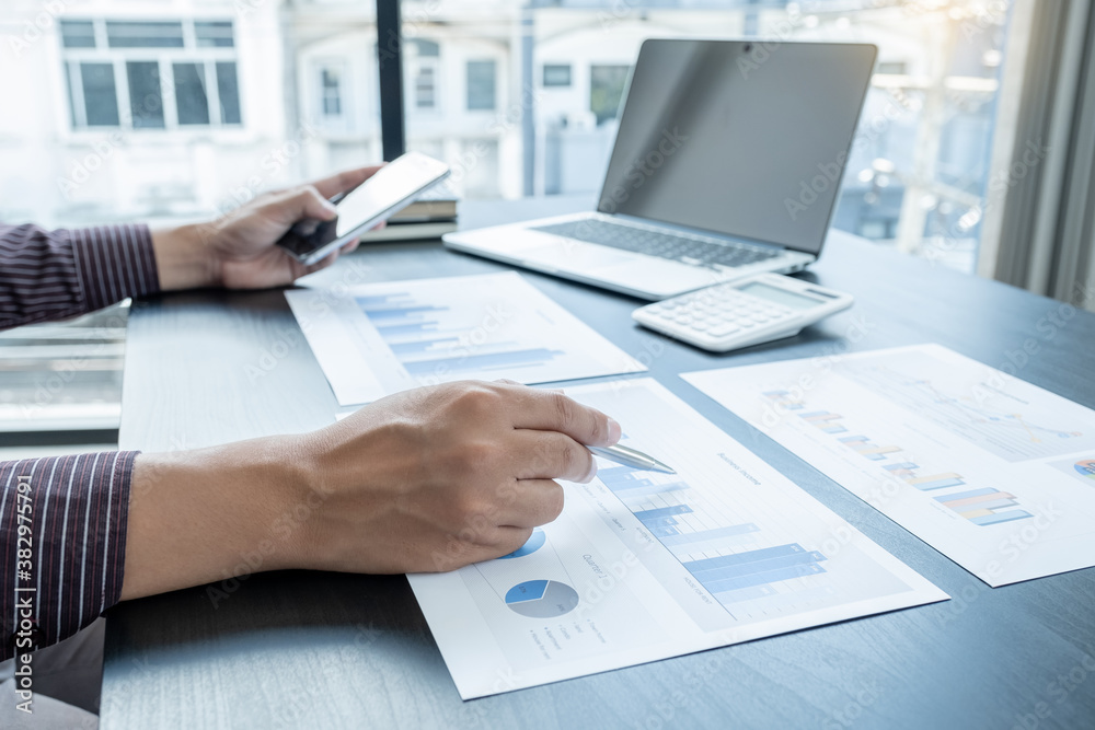 The hands of a male businessman are analyzing and calculating the annual income and expenses in a financial graph that shows results To summarize balances overall in office The hands of a male businessman are analyzing and calculating the annual income and expenses in a financial graph that shows results To summarize balances overall in office