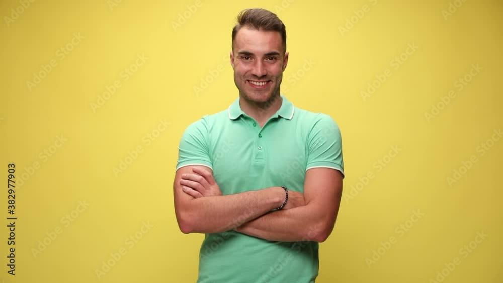 casual guy standing with his arms crossed, smiling, sticking his hands in his pocket, looking away then looking at the camera and laughing on yellow background casual guy standing with his arms crossed, smiling, sticking his hands in his pocket, looking away then looking at the camera and laughing on yellow background