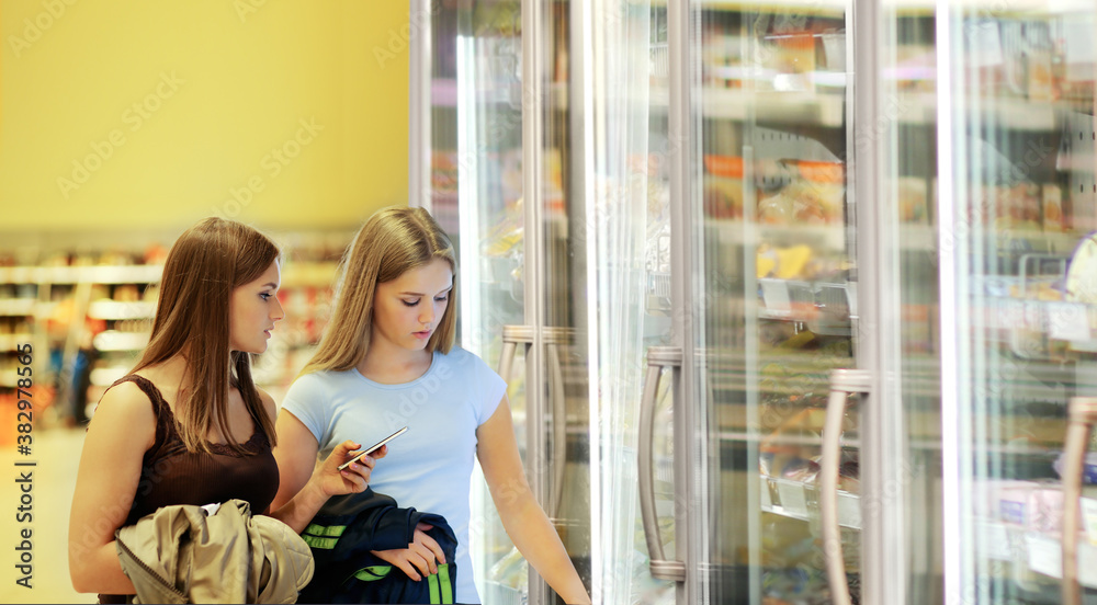 two girl  choosing a dairy products at supermarket
