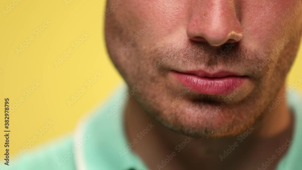 close up on a casual man's sexy lips on yellow background close up on a casual man's sexy lips on yellow background