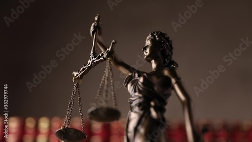 justice statue represented by blindfolded lady holding a balance and a sword signifying power and impartiality, rotating in a university room with a background made of books photo