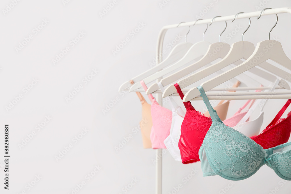Фотография Clothes rack with stylish bras on light background