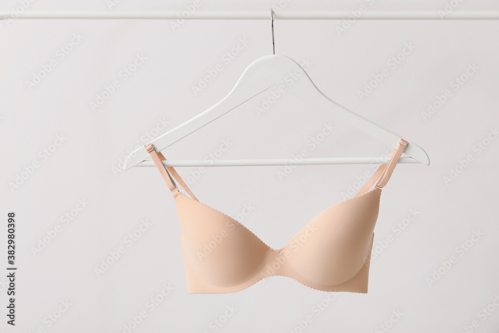 Hanger with stylish bra on light background - obrazy, fototapety, plakaty 