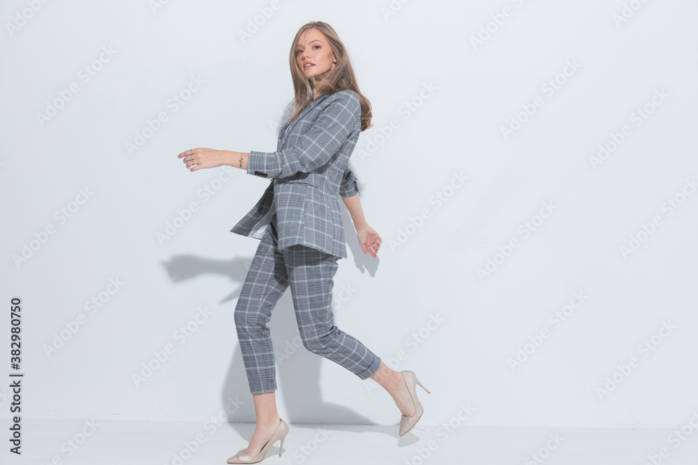 Side view of charming fashion businesswoman wearing suit while running