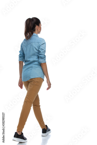 Fotografia Side rear view of smart casual woman walking, wearing shirt