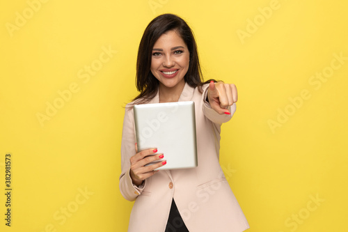 young woman in pink suit holding tab and smiling