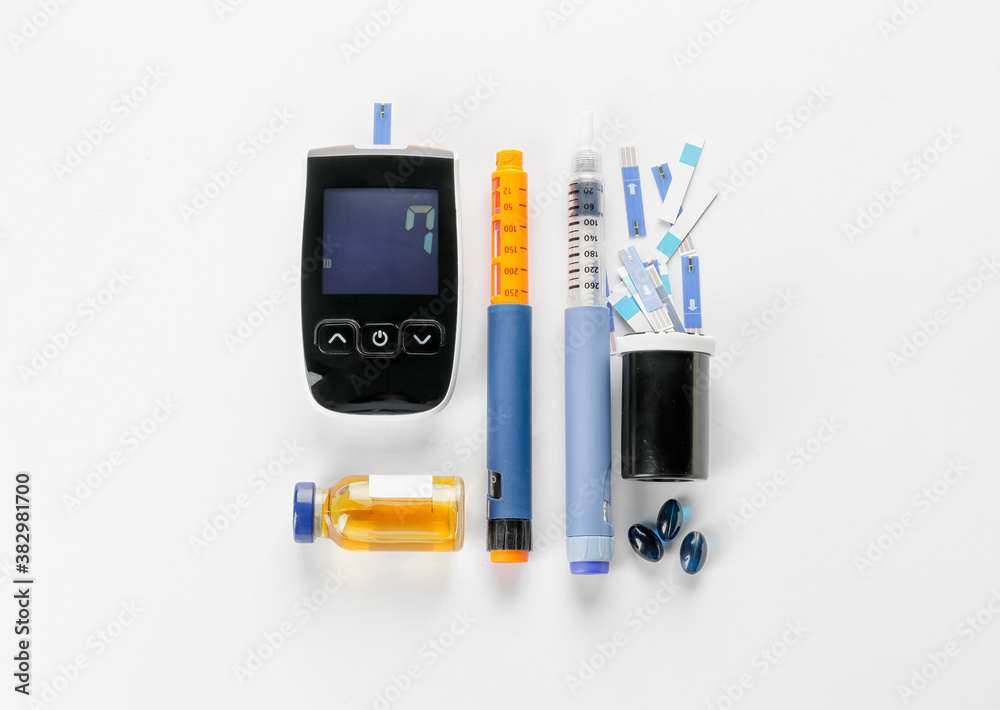 Glucometer, strips, medications and syringes on white background. Diabetes concept Glucometer, strips, medications and syringes on white background. Diabetes concept