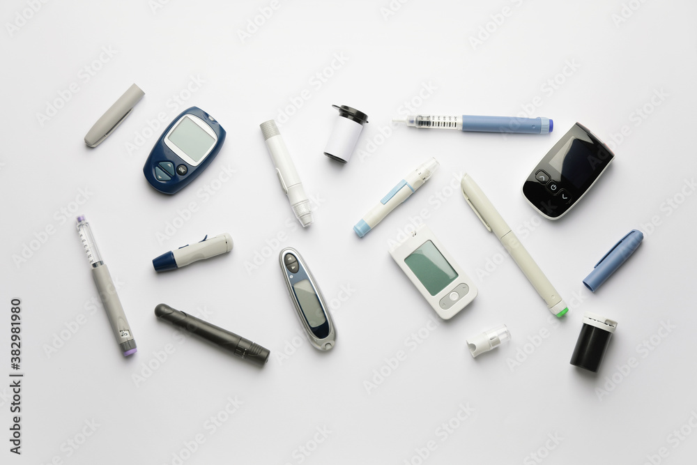 Glucometers with lancet pens and syringe on white background Glucometers with lancet pens and syringe on white background