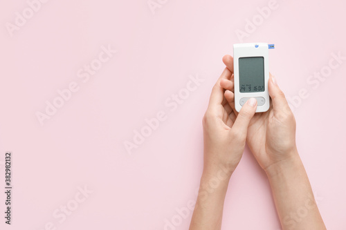 Female hands with glucometer on color background. Diabetes concept photo